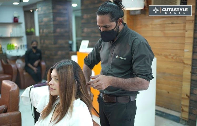 A CUT & STYLE artist styling a guest's hair